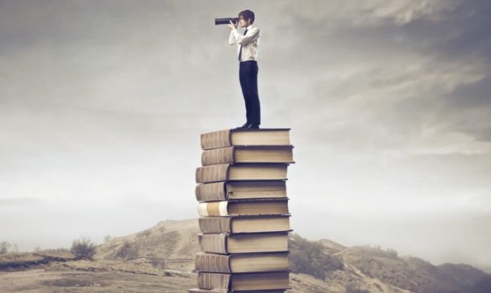self growth; man standing on stack of books